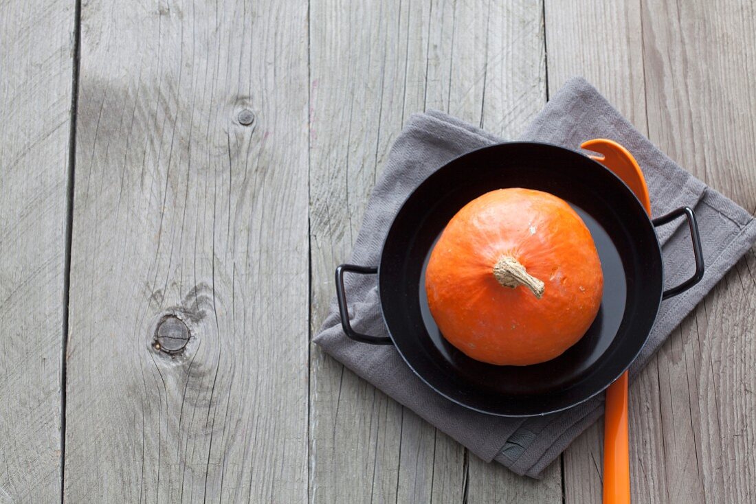 A whole raw Hokkaido pumpkin in a pan (seen from above)