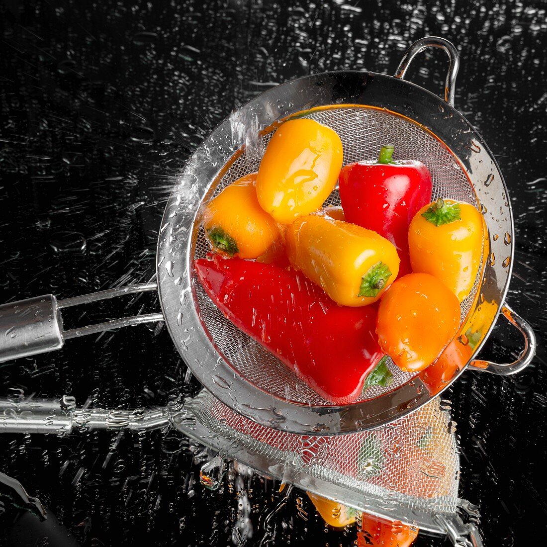Mini peppers being washed in a sieve