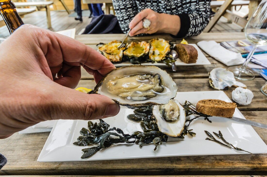 A person eating an Zeeland oyster in a restaurant