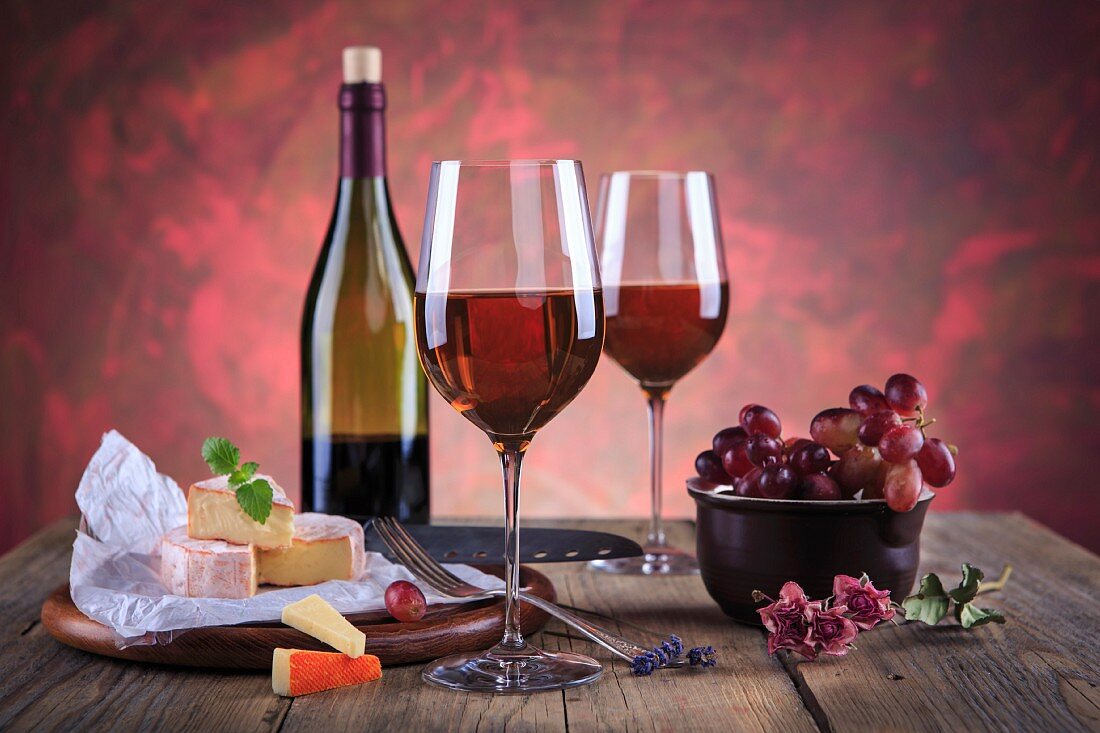 An arrangement of red wine, cheese and grapes