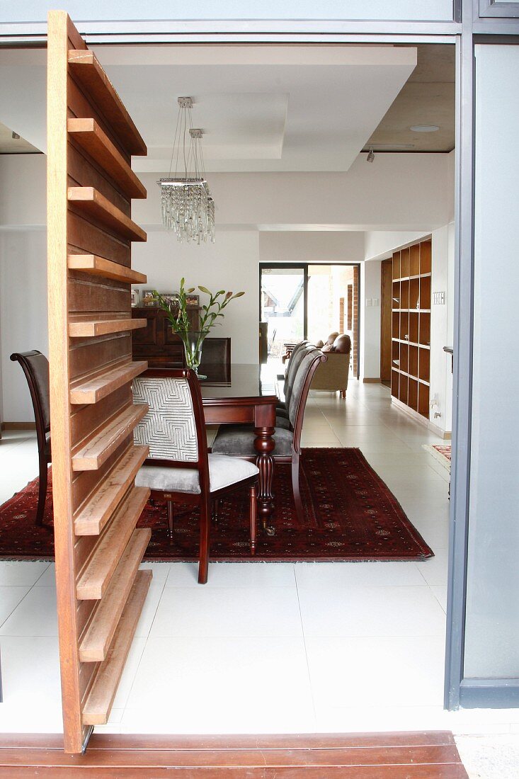 Period furniture in modern interior with white tiled floor, suspended ceiling elements and swivelling façade segment