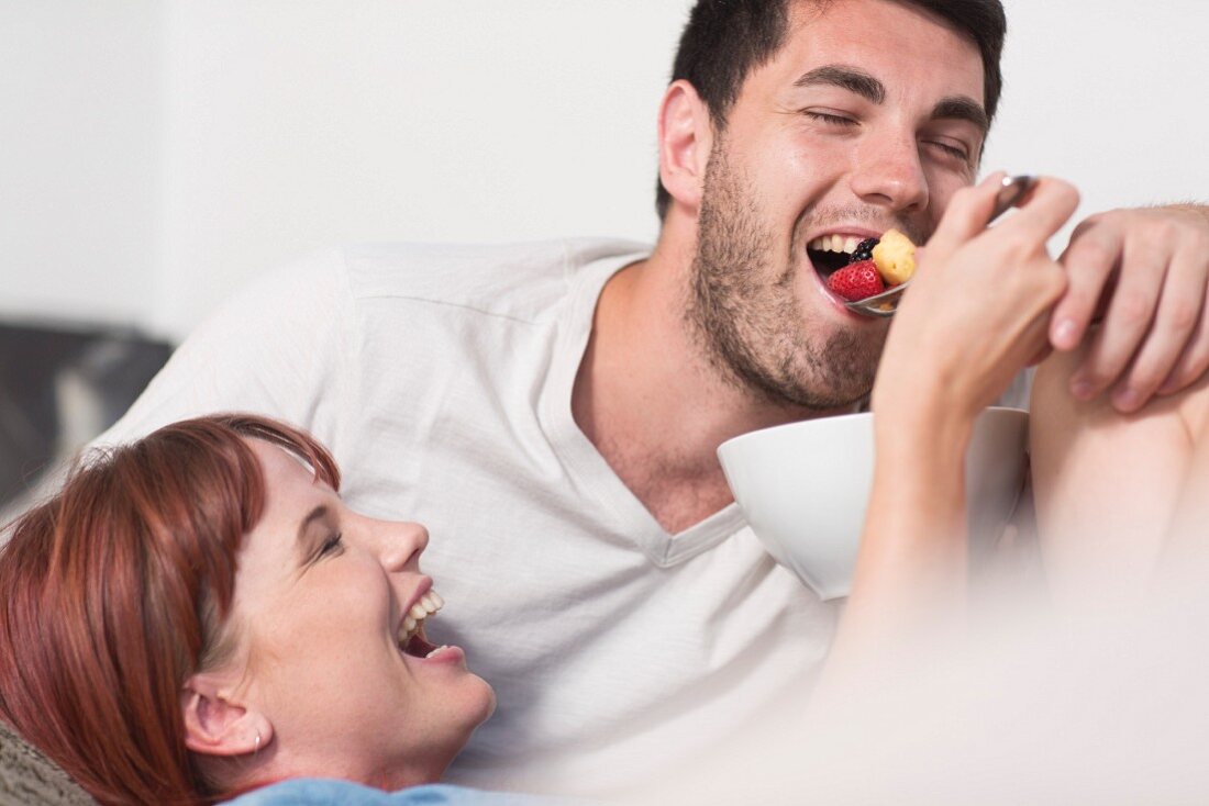 Frau füttert Mann mit Obstsalat