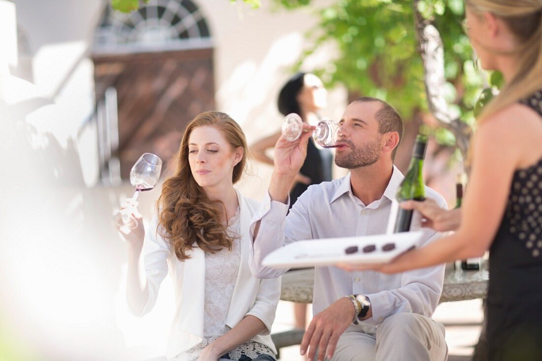 A young couple tasting red wine outside