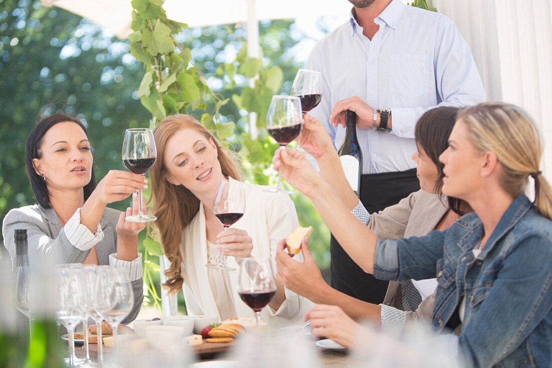 Junge Frauen bei der Rotweinverkostung an Tisch im Freien