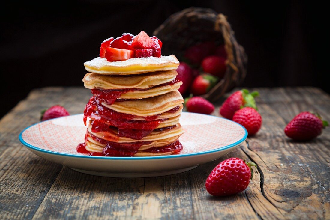 Ein Stapel Pancakes mit Erdbeeren & Erdbeermarmelade auf Teller