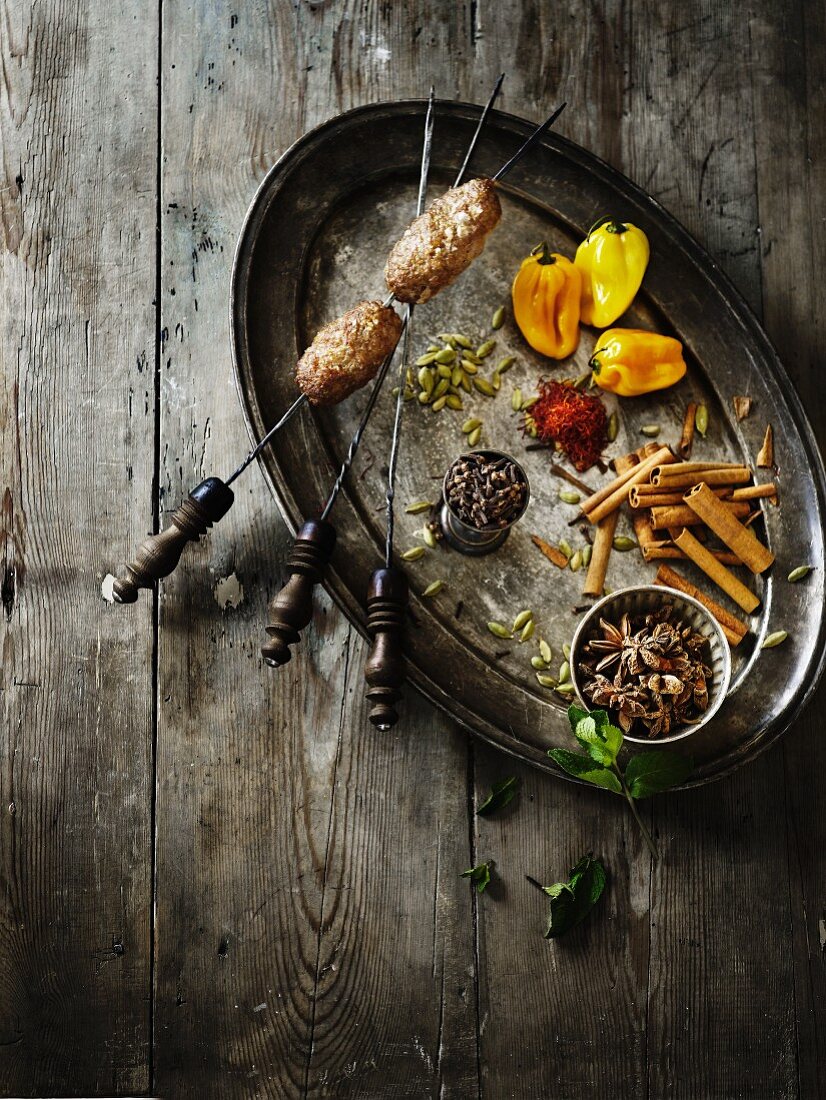 Various spices on an oval metal plate with a fish skewer