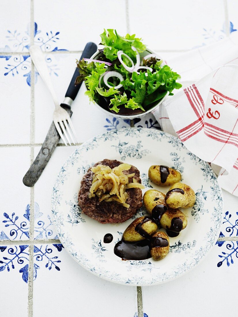 Hacksteak mit Apfel-Zwiebel-Gemüse, ofengebratenen Kartoffeln und Balsamicosauce, dazu Salat