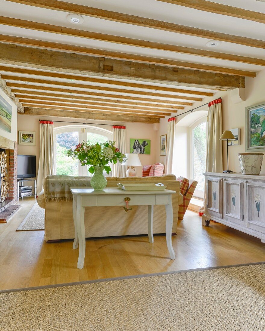 Konsolentisch an Sofa in ländlichem Wohnzimmer mit Holzbalkendecke und elegantem Flair