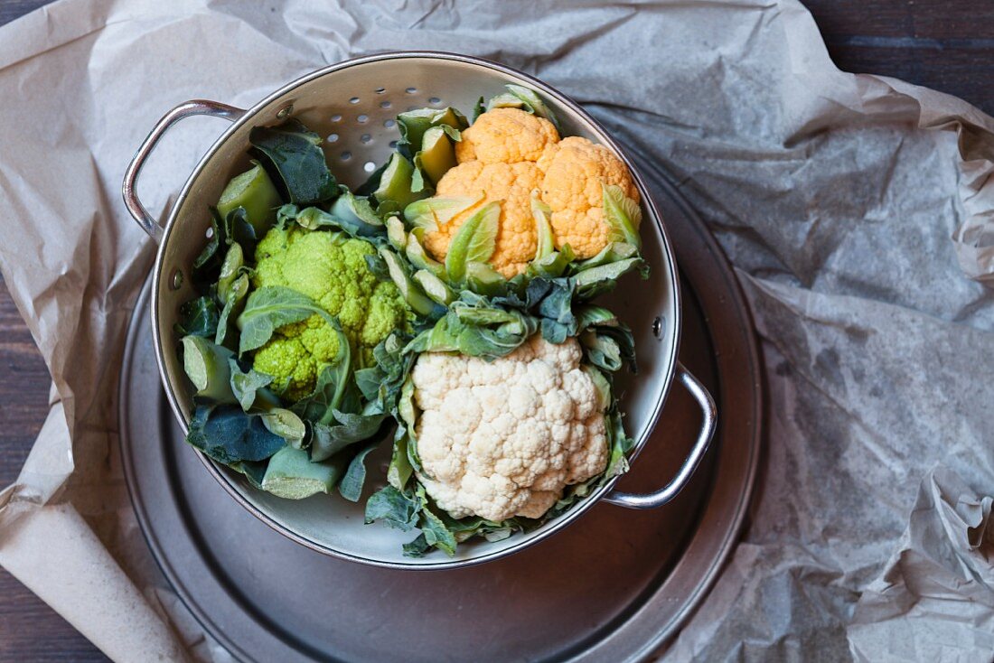 Various different coloured cauliflowers on a pewter plate