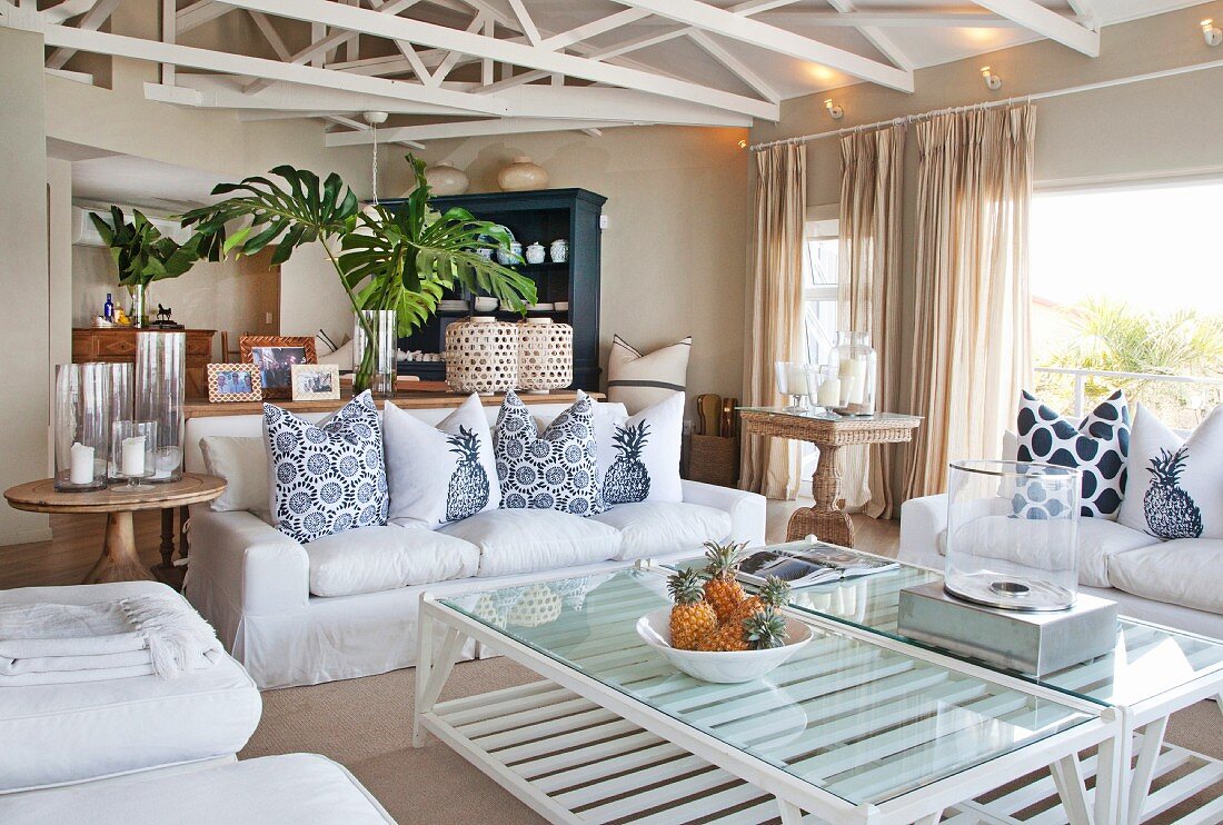 Open-plan living area with white loose-covered furniture and painted lattice girders in elegant country-house interior