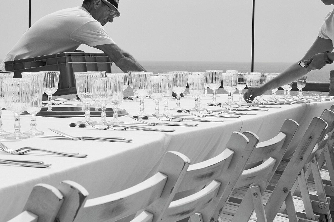 Tables for a wedding being laid outside (black-and-white shot)