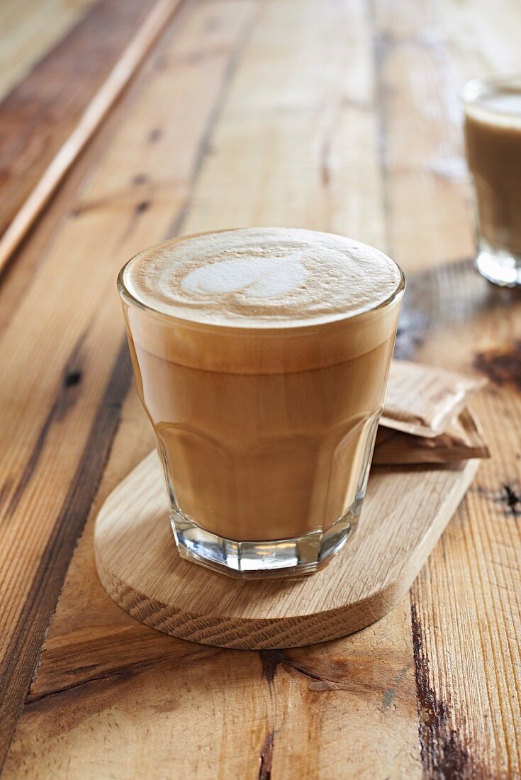 Cappuccino im Glas mit dekorativem Milch-Herz