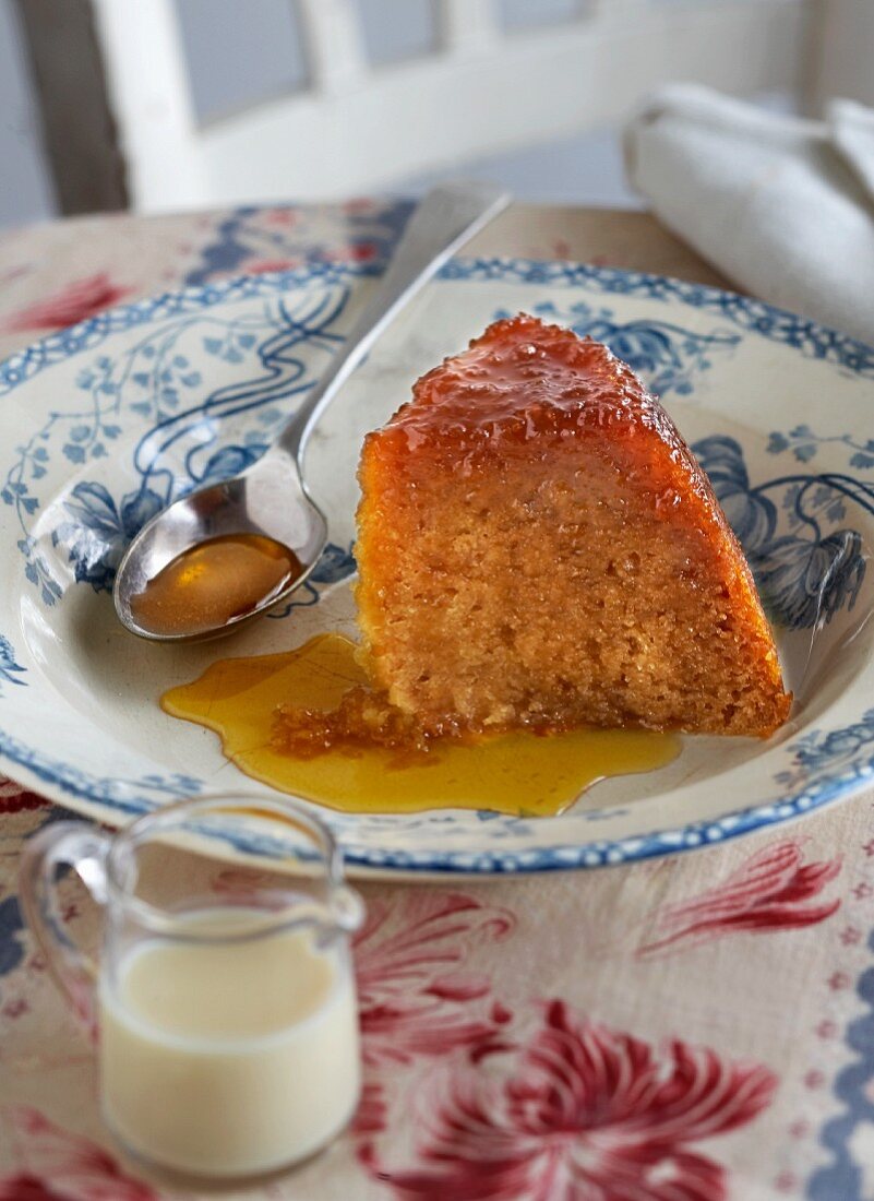A slice of sponge cake with orange syrup on a plate