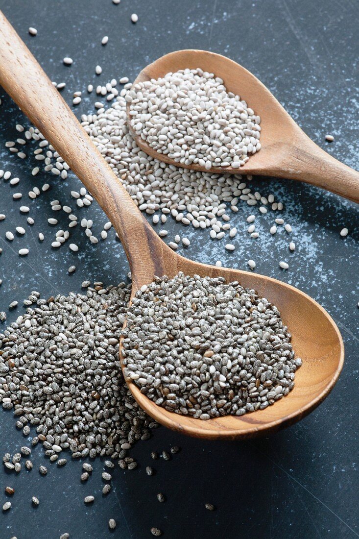 Black and white chia seeds on wooden spoons