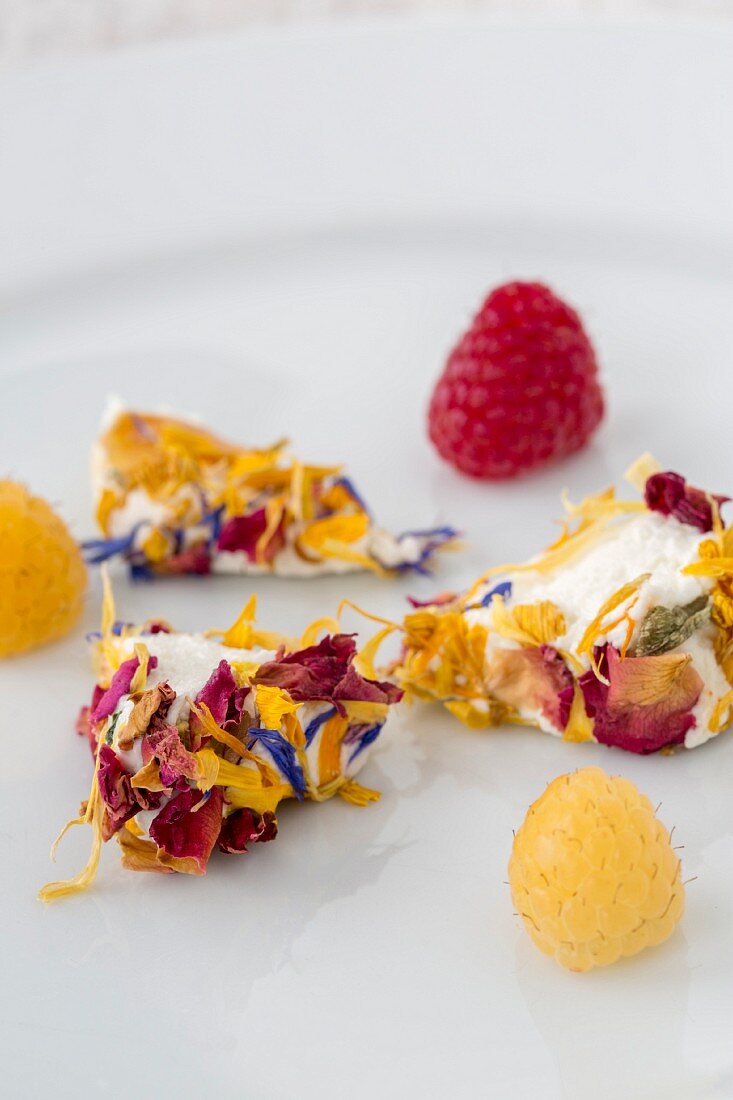 Ziegenkäseecken mit Essblüten und frischen Himbeeren