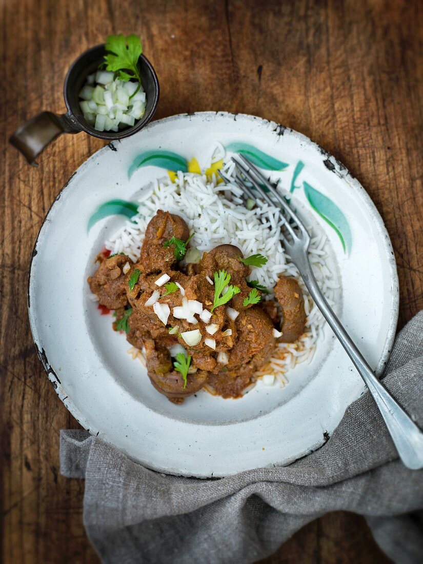 Indian kidney curry with chopped onions and coriander on a bed of rice