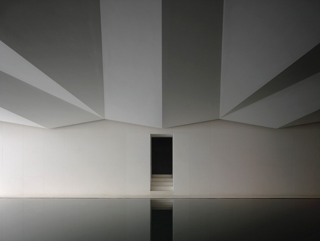 Dramatic ceiling and narrow door with steps reflected in indoor swimming pool