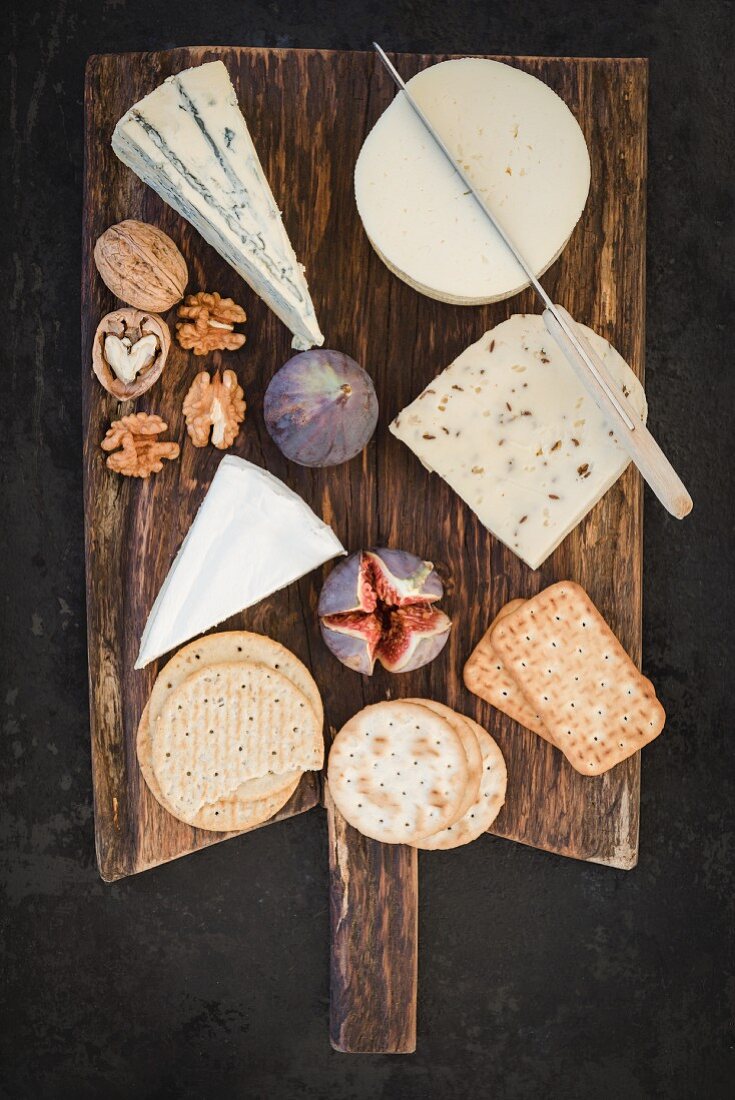 A cheese platter featuring Havarti, Brie, Danish caraway cheese, blue cheese, figs, crackers and nuts
