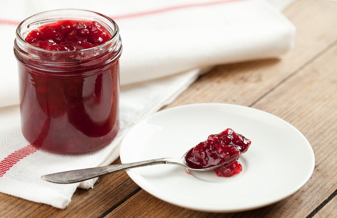 Rote Beerenmarmelade im Glas und auf Löffel