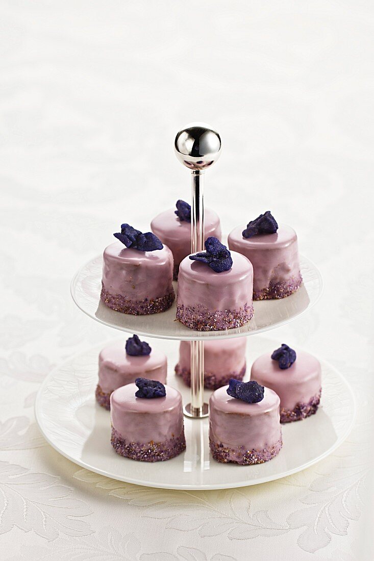 Punch cakes with candied violets on a cake stand