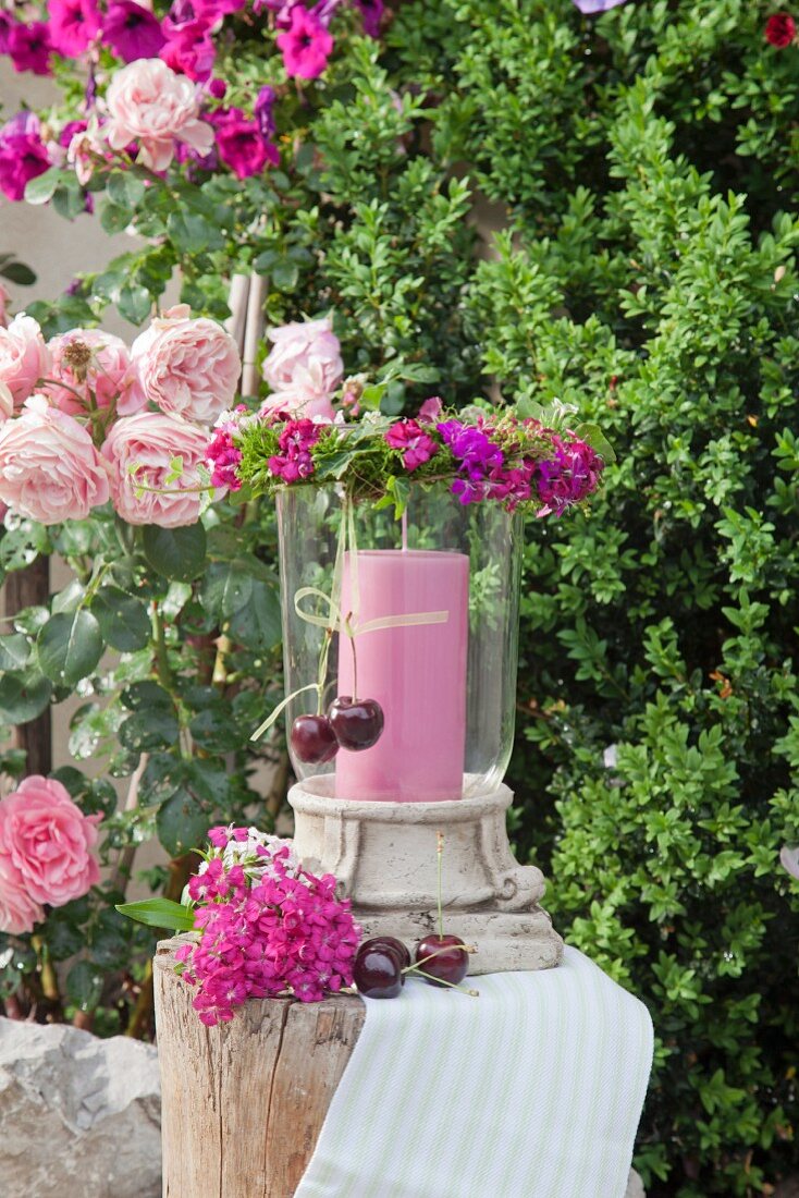 Pink candle in lantern and wreath of pink Sweet Williams in garden