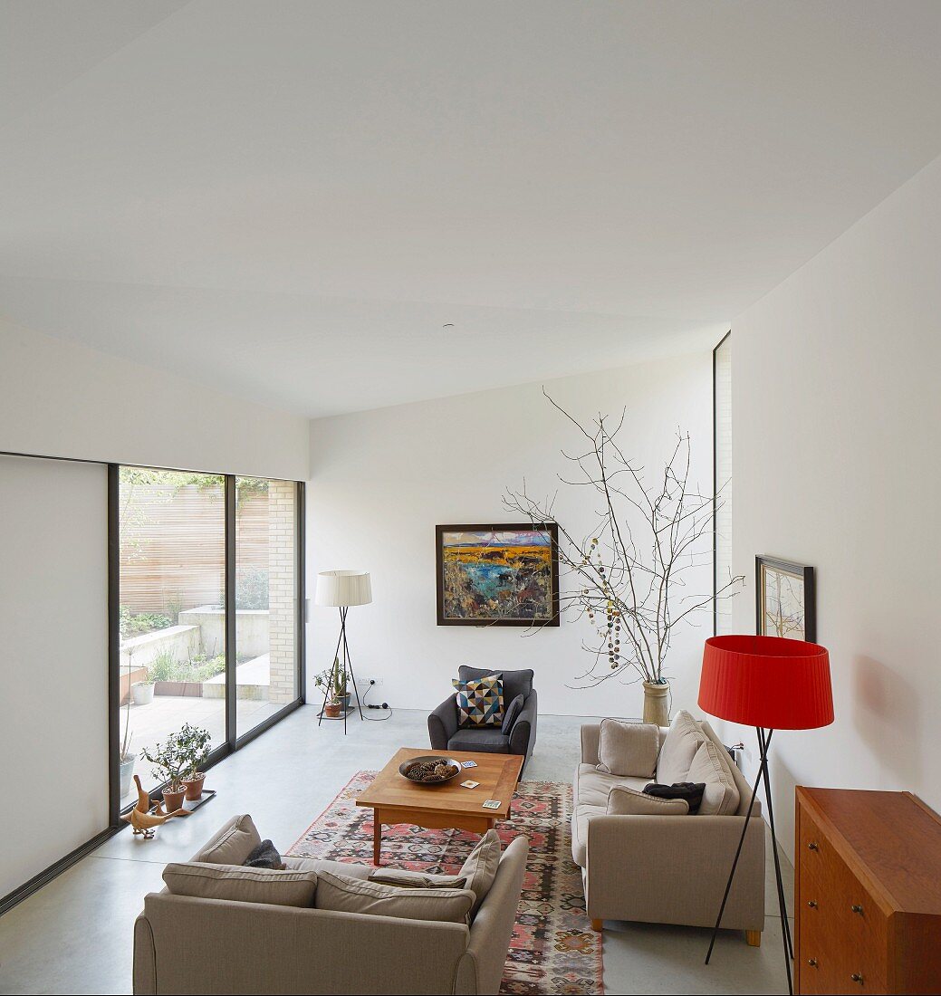 View from gallery into comfortable living area with beige sofas and standard lamp with red lampshade