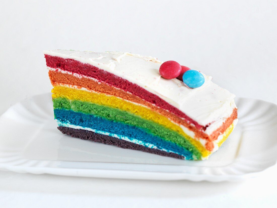 Ein Stück Rainbow Cake mit bunten Schokolinsen