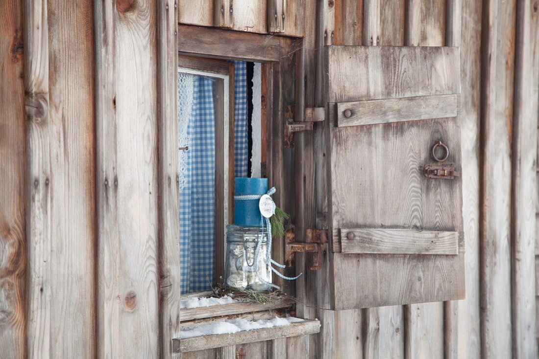 Adventsdekoration auf Fensterbrett von rustikaler, verwitterter Hütte