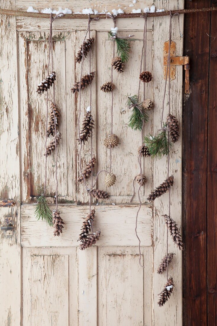 Mobile made from various conifer cones and twigs hung on old door