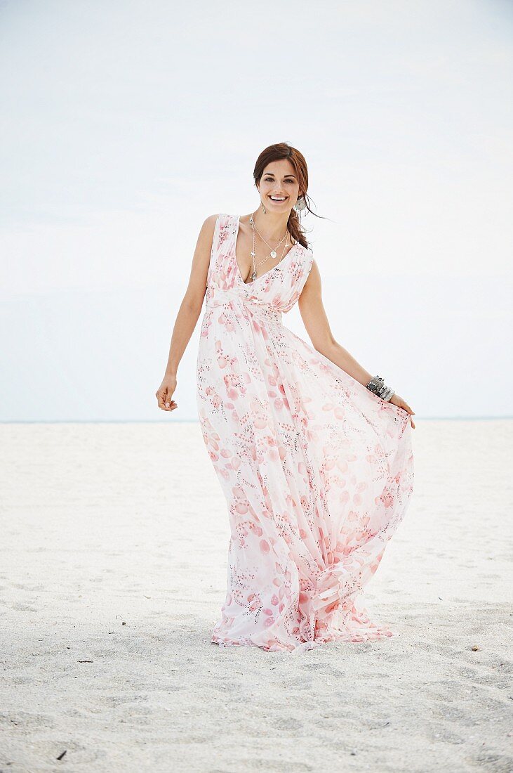 Brünette Frau in langem Sommerkleid am Strand