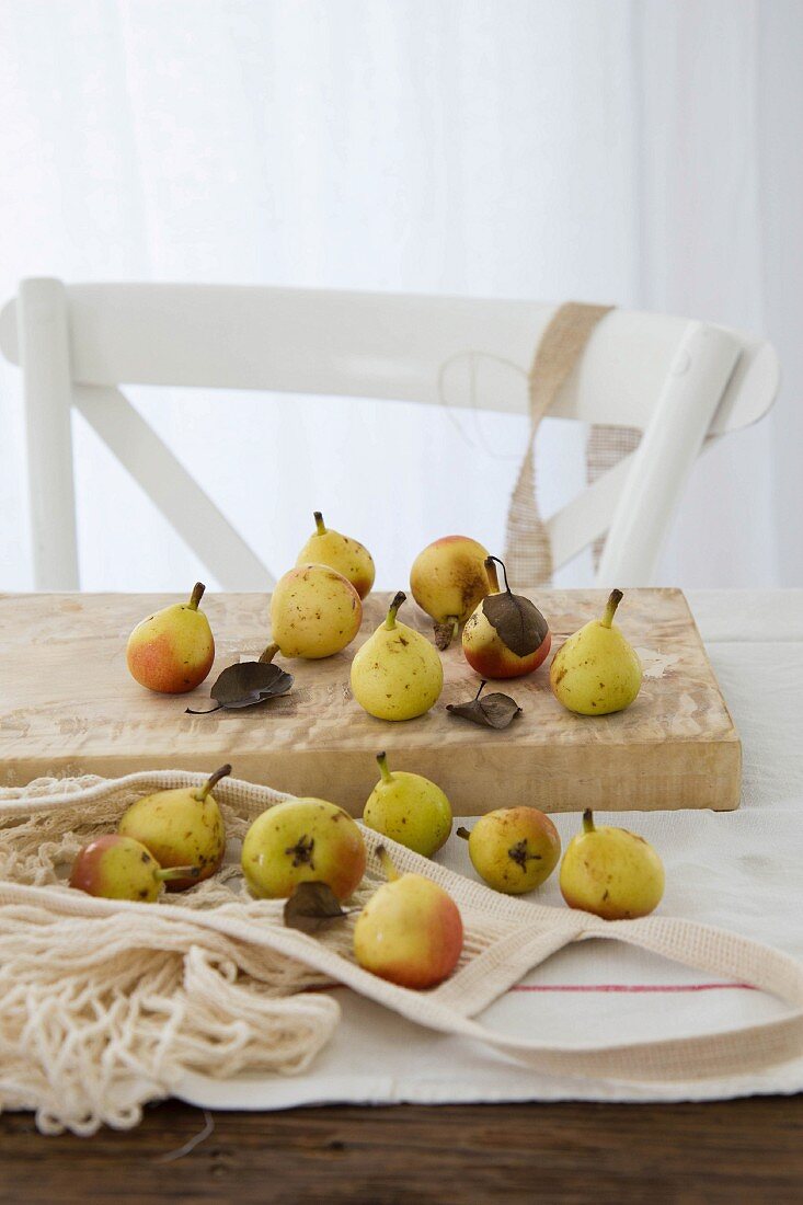 Small pears with leaves on a wooden chopping board