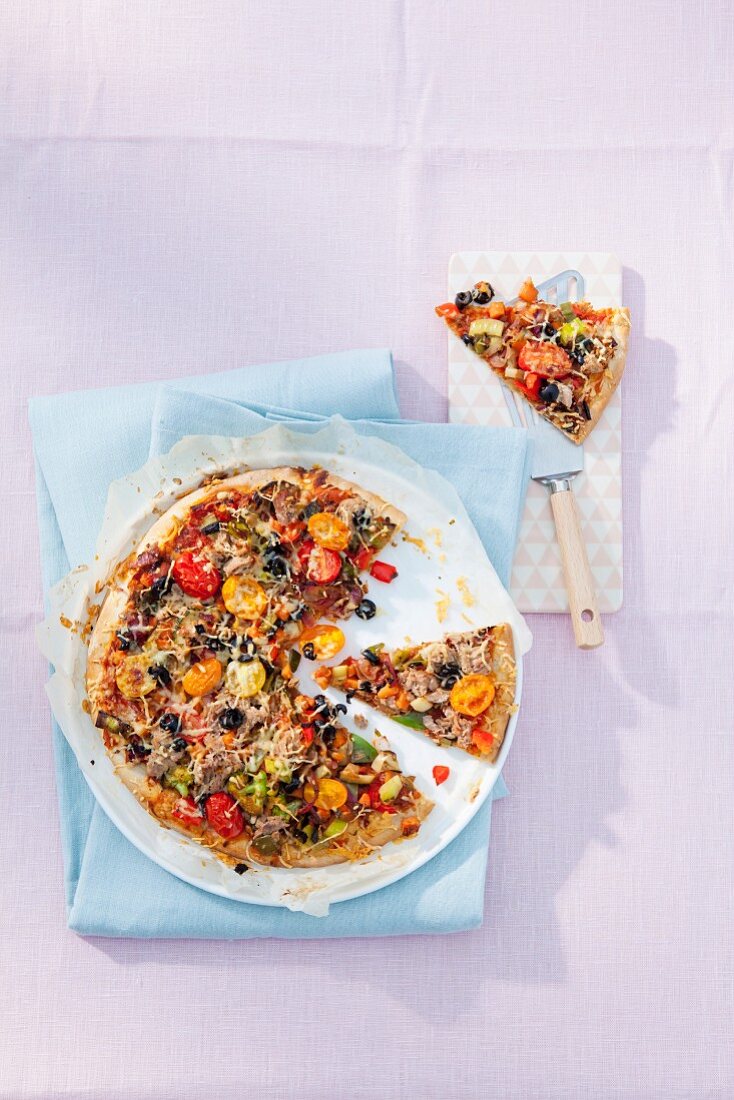 Homemade tuna fish pizza with cherry tomatoes and olives (seen from above)