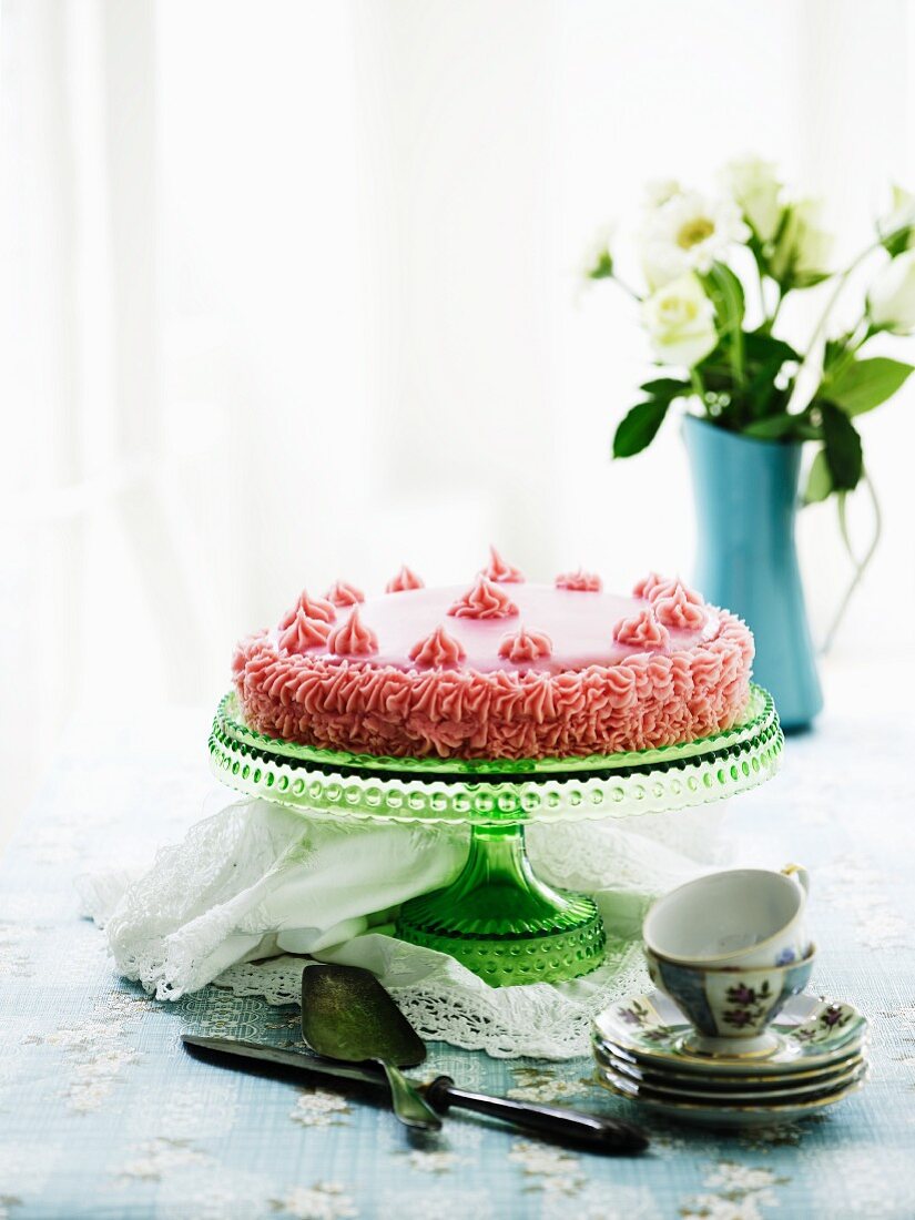 A pink buttercream cake on a cake stand