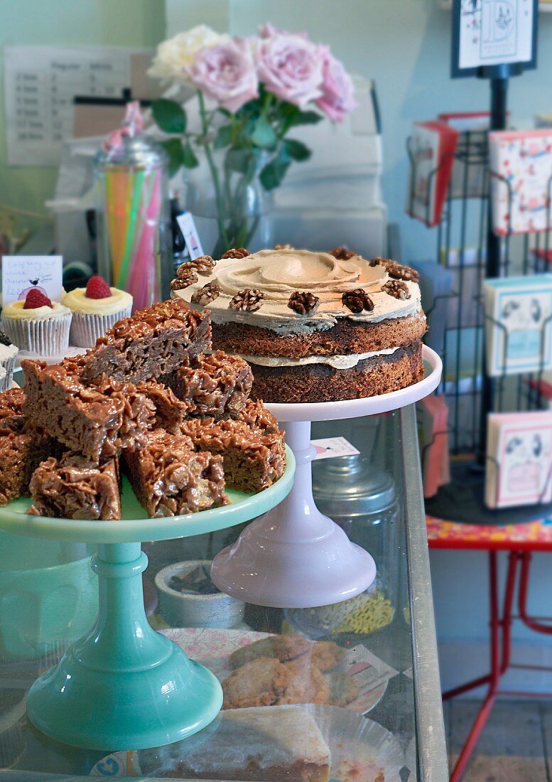 Various cakes and cupcakes on top of a display cabinet in a restaurant