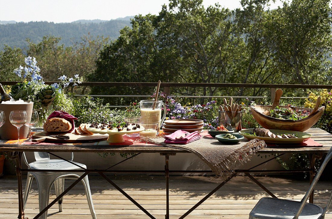 A wooden table laid on a terrace for a summer party in the countryside