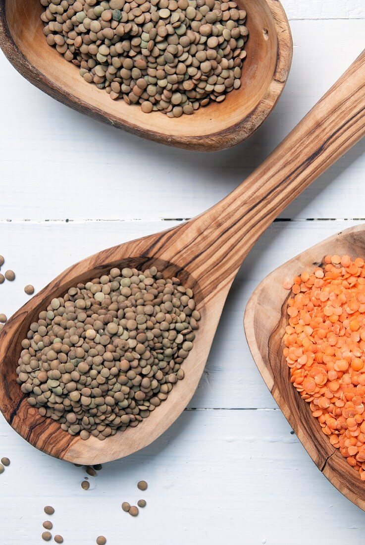 Red and green lentils on wooden spoons