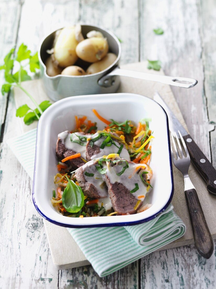 Steamed veal medallions on a bed of herbs and vegetables