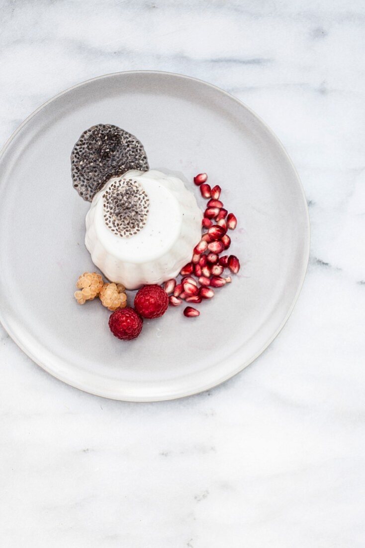 Panna cotta with chia seeds, pomegranate seeds and raspberries