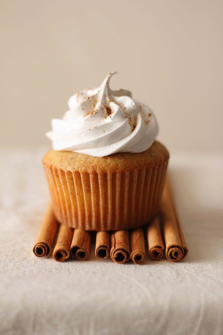 A chai cupcake on cinnamon sticks