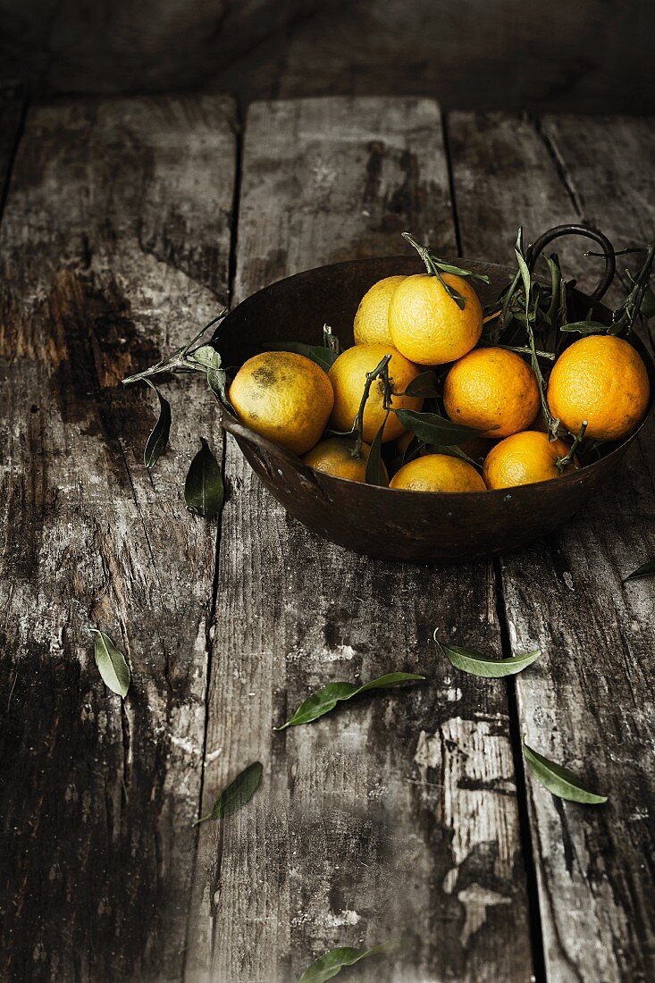 A bowl of mandarins on a wooden surface