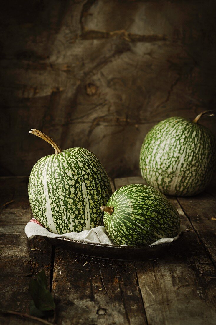 Three green pumpkins on a wooden table