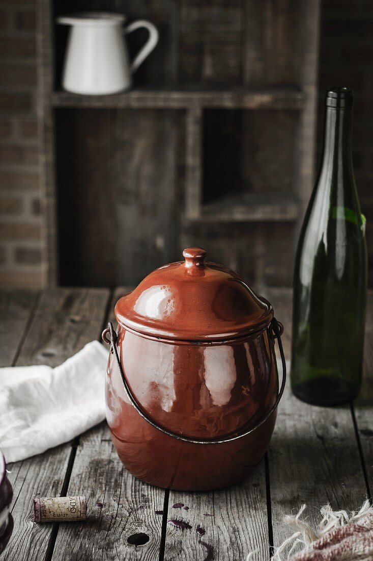An old cooking pot and an empty wine bottle on a wooden table