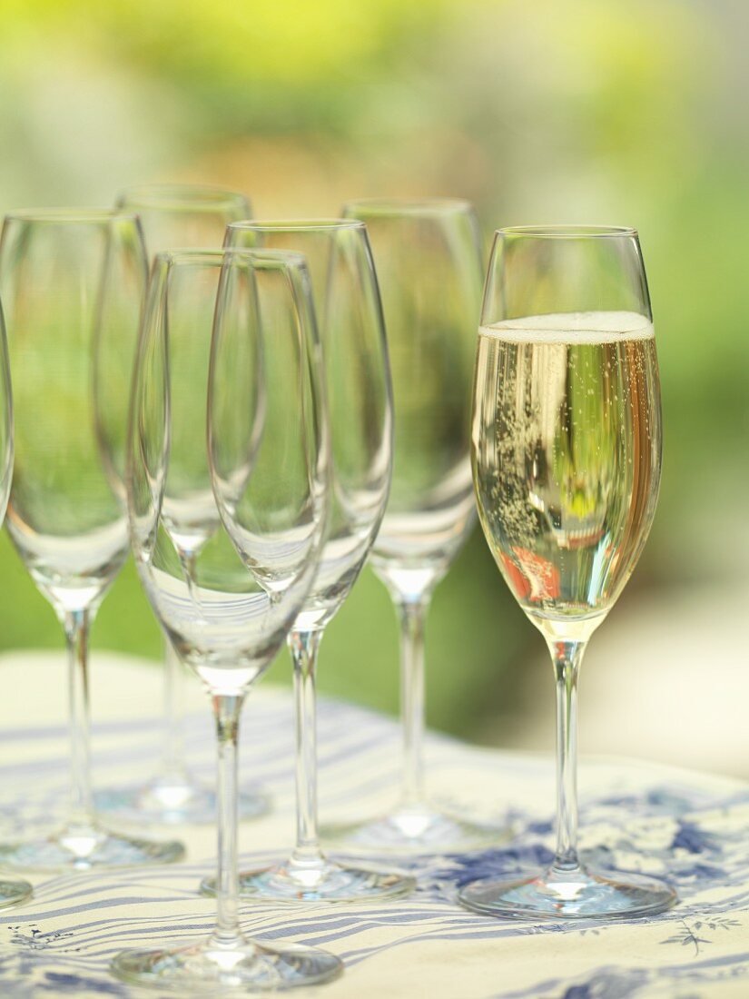 Champagnerglas neben einigen leeren Gläsern