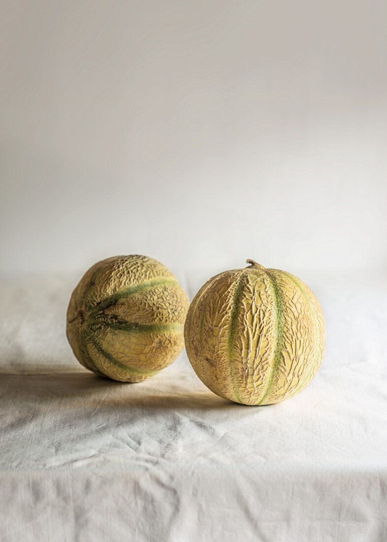 Zwei Cantaloupemelonen auf Tischtuch