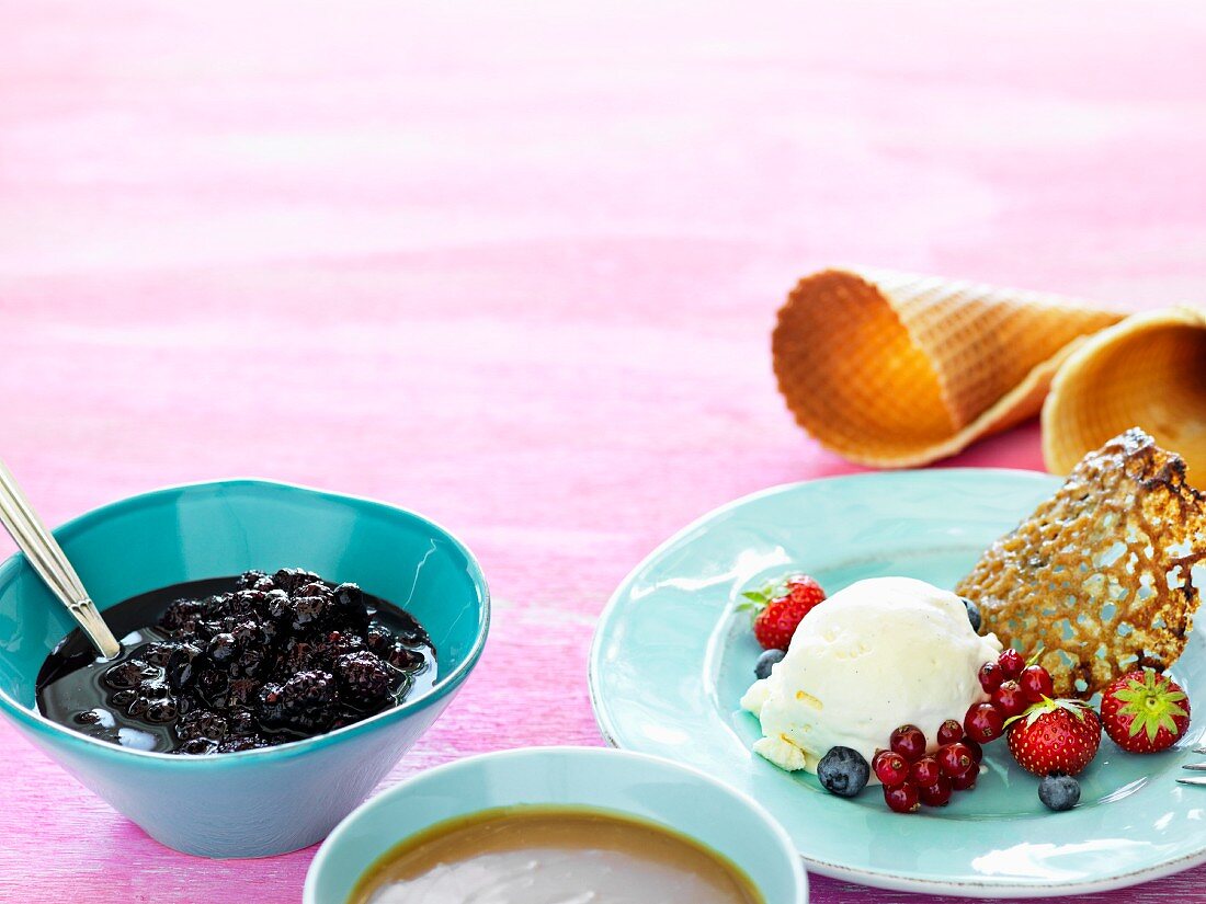 Vanilleeis mit Beeren und Lakritzehippe, dazu Eiswaffeln, Beeren- und Karamellsauce