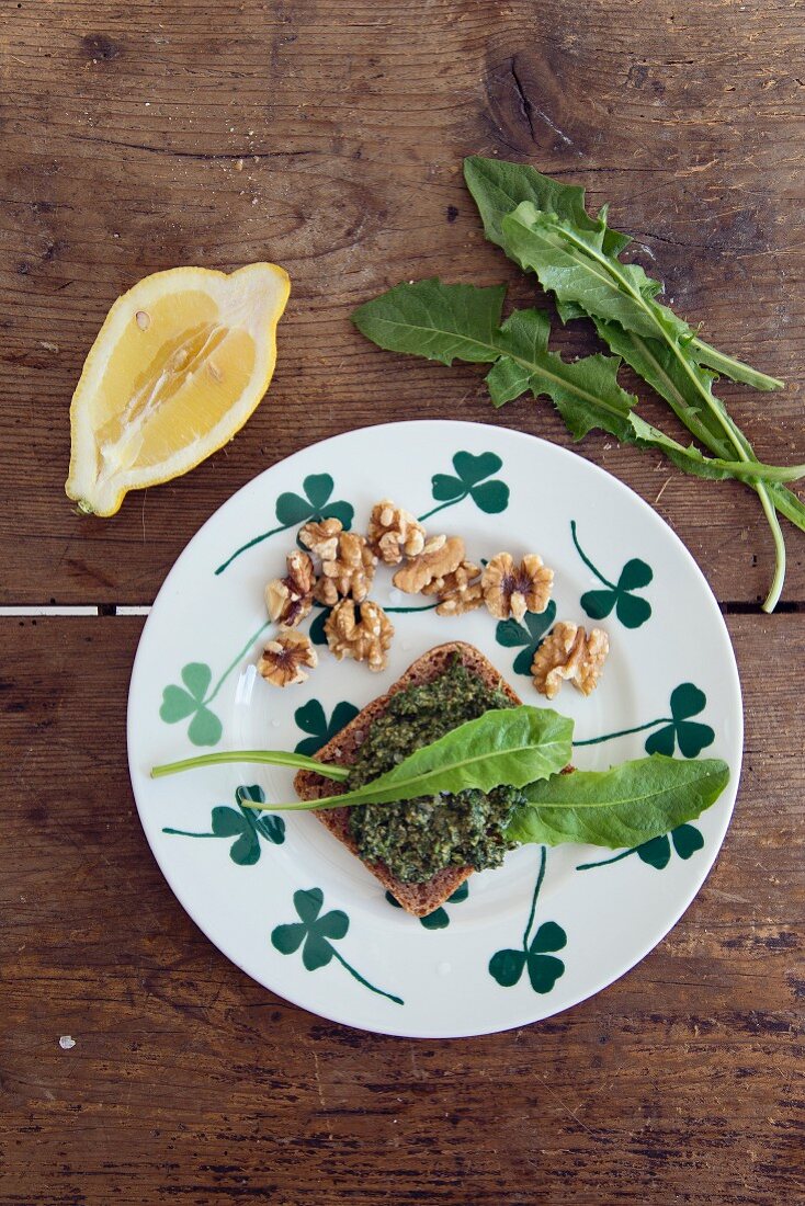 A plate of herbs bread and dandelion leaves on a wooden table