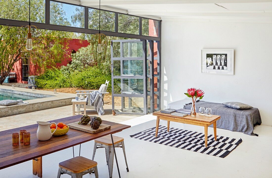 Dining table with classic stools and couch in front of open terrace door