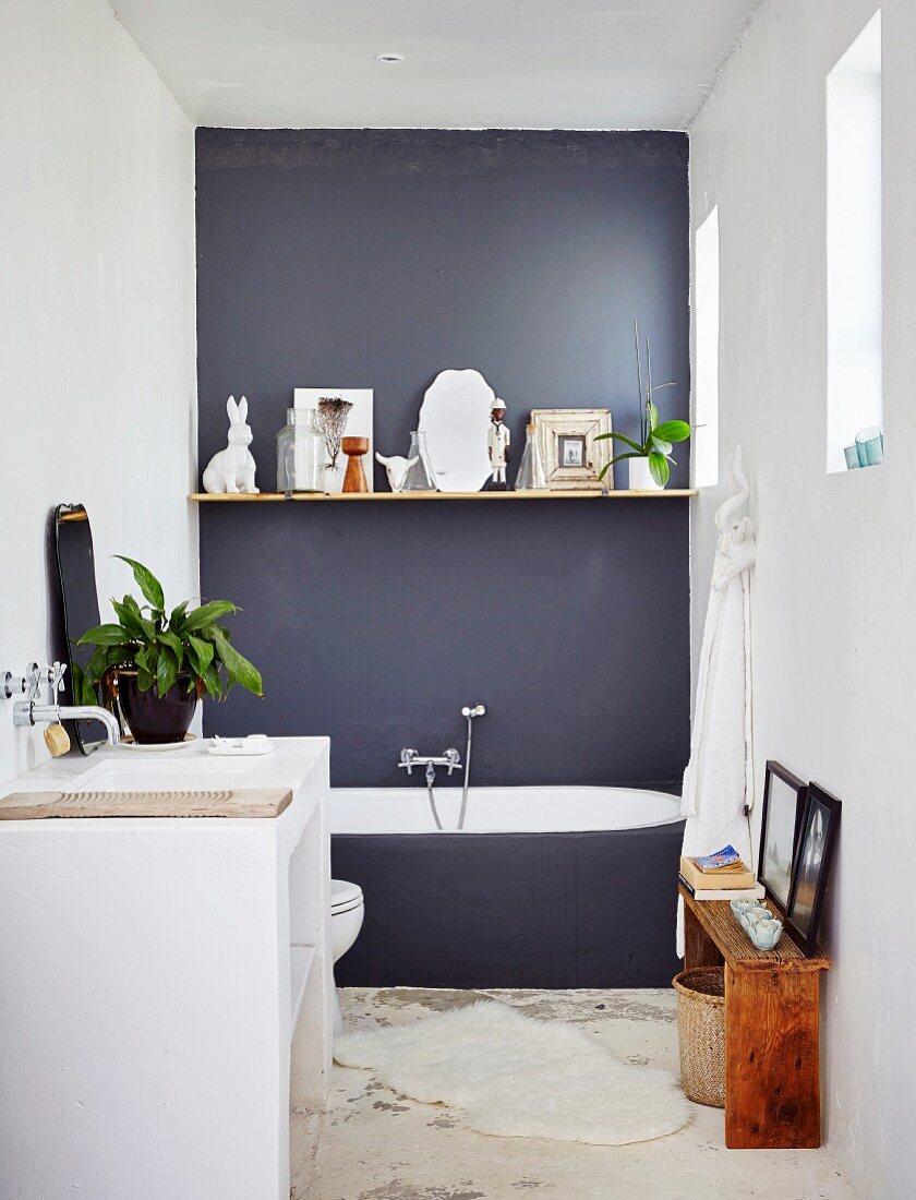 Floating shelf on dark grey wall and masonry washstand in minimalist bathroom