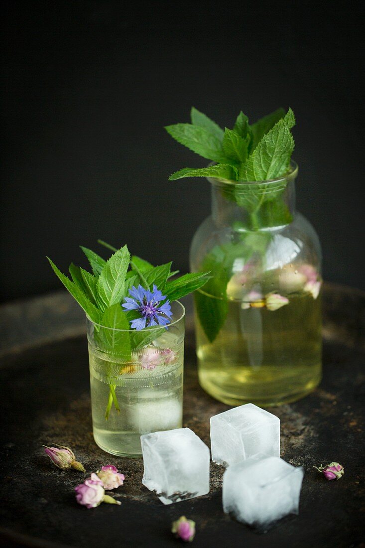 Iced tea with fresh mint, ice cubes, dried roses and cornflowers