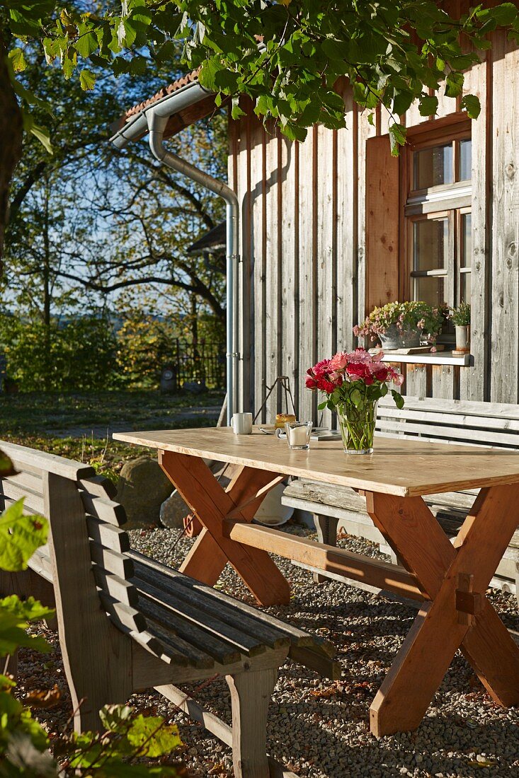 Rustikaler Sitzplatz in der Herbstsonne vor Holzhaus